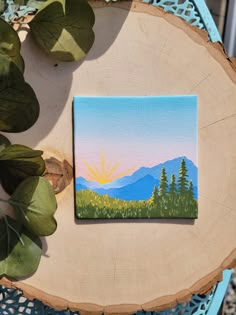 a painting is sitting on top of a piece of wood next to some plants and a potted plant