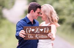 a man and woman holding up a wooden sign