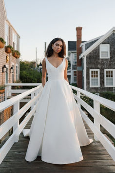 a woman in a white wedding dress standing on a bridge