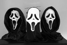 three white masks with black hoods on top of a table