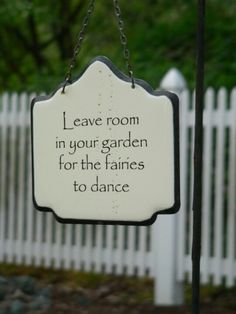 a sign hanging from the side of a white picket fence that says leave room in your garden for the fairies to dance