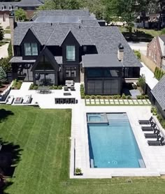 an aerial view of a house with a swimming pool in the foreground and lawn