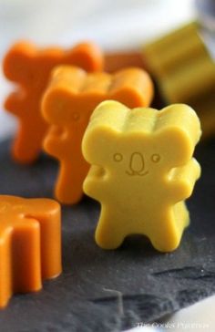 three gummy bears sitting next to each other on top of a black surface with yellow and orange ones