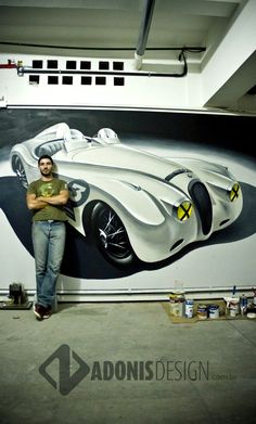 a man standing in front of a painting of a race car