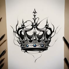 a drawing of a crown with blue eyes on paper next to pens and pencils