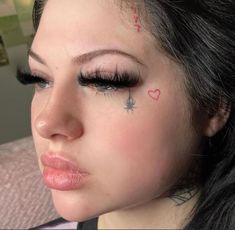 a close up of a person with tattoos on her face and eyeliners in the shape of hearts