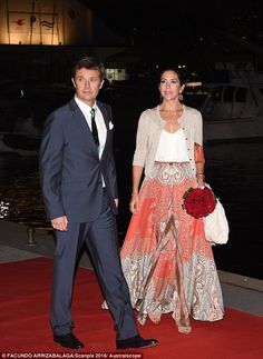 the man and woman are walking together on the red carpet at night, dressed in formal attire