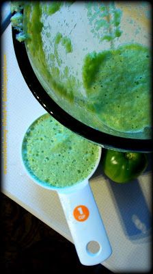 a green smoothie is being made in a blender with an orange on the side