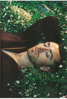 a man laying in the grass with his eyes closed and head tilted to the side