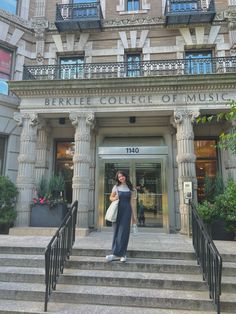 a woman standing in front of a building with stairs leading up to the entry door