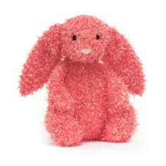 a pink stuffed animal sitting on top of a white surface with one eye open and the other half closed