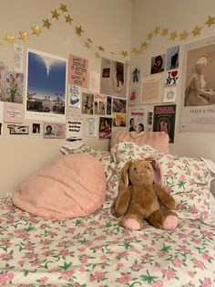 a teddy bear sitting on top of a bed in a room with pictures and posters