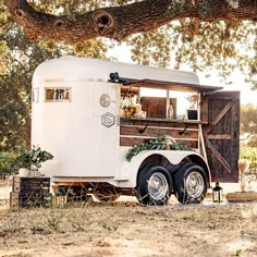 a food truck parked under a large tree