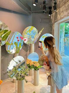 a woman taking a selfie with her cell phone in front of mirrors and flowers