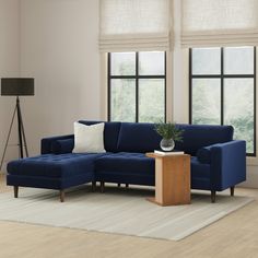 a living room with two windows and a blue couch in front of a white rug