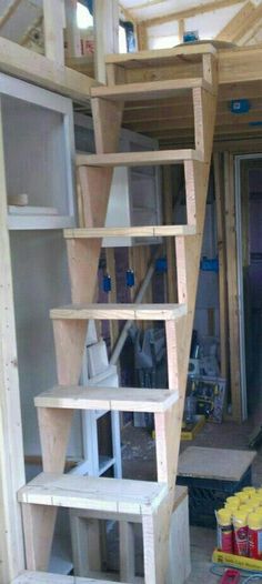 the inside of a house being built with wooden shelves and ladders on each side