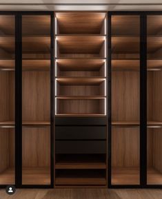 an empty walk - in closet with wooden shelves and lights on the walls, along with hardwood flooring