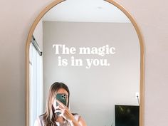 a woman taking a selfie in front of a mirror that says the magic is in you