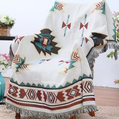 a chair with a blanket on it sitting in front of a potted plant and flowers