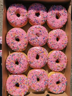 a box filled with lots of pink frosted donuts covered in sprinkles