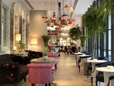 the interior of a restaurant with tables, chairs and potted plants hanging from the ceiling