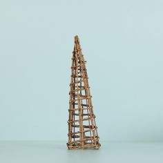 a small wooden structure made out of sticks on a table next to a blue wall