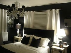 a black and white bedroom with chandelier, bed, nightstands and windows