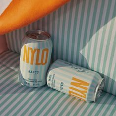 two cans of nylo are sitting next to each other on a striped bed sheet