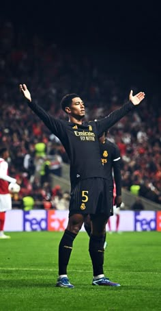 a man standing on top of a soccer field holding his arms up in the air