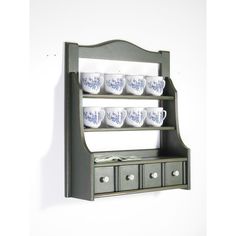 a wall mounted shelf with cups on it and drawers in the bottom section, along with two mugs