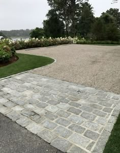 a stone walkway with grass and flowers in the background