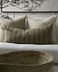 a white couch with two pillows and a bowl on the floor in front of it