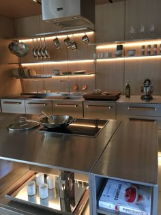 a modern kitchen with stainless steel appliances and cookware on the counter top, along with books