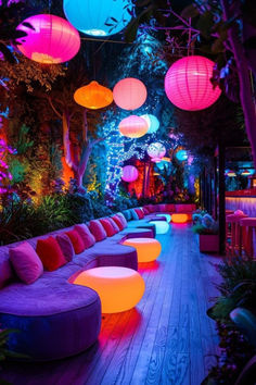 an outdoor seating area is lit up with colorful lights and lanterns hanging from the ceiling