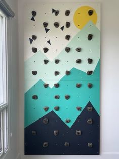 a climbing wall with rocks on it and mountains painted on the wall in the background