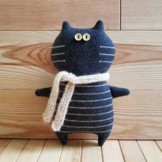 a black cat stuffed animal with a scarf around it's neck on a wooden floor