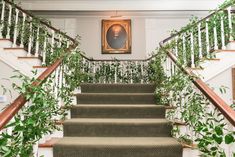 the stairs are covered with green plants in front of a framed portrait on the wall