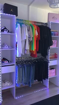 an organized closet with clothes and shoes on shelves, lights in the ceiling and white walls