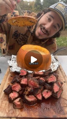 a man with a hat is eating some food on a wooden cutting board and smiling at the camera