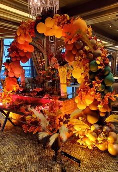 an arrangement of oranges and pumpkins on display in a room with chandelier