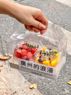 a person holding a plastic container filled with fruit