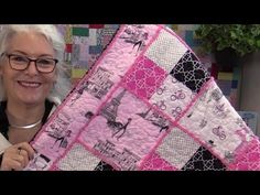 a woman holding up a pink and black quilt