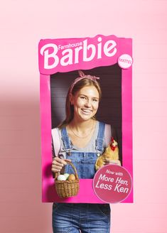 a woman holding up a barbie doll with an egg in her hand and a sign that says barbie