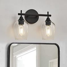 a bathroom vanity with two lights and a mirror on the wall next to it,