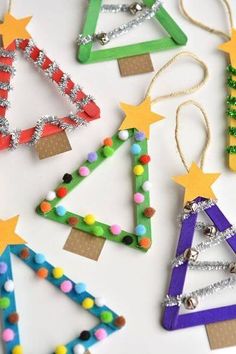 christmas tree ornaments made out of popsicle sticks and beaded beads are displayed on a white surface