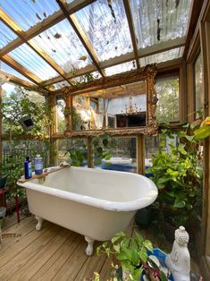 a bathtub sitting on top of a wooden floor next to a plant filled wall