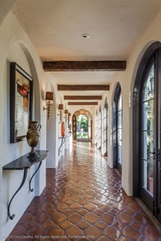 the hallway is lined with arched windows and stone flooring, along with an iron console table