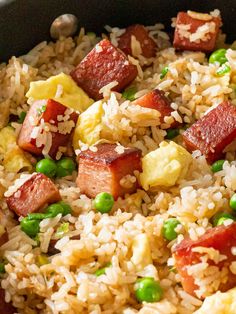 rice, peas and sausage are mixed together in a skillet on top of the table