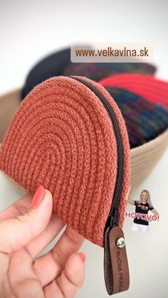 a hand holding a zippered pouch in front of a bowl filled with yarns