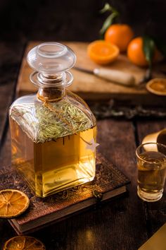 a bottle of tea sitting on top of a wooden table next to sliced oranges